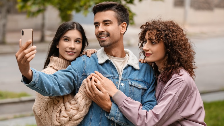 three people taking a selfiie