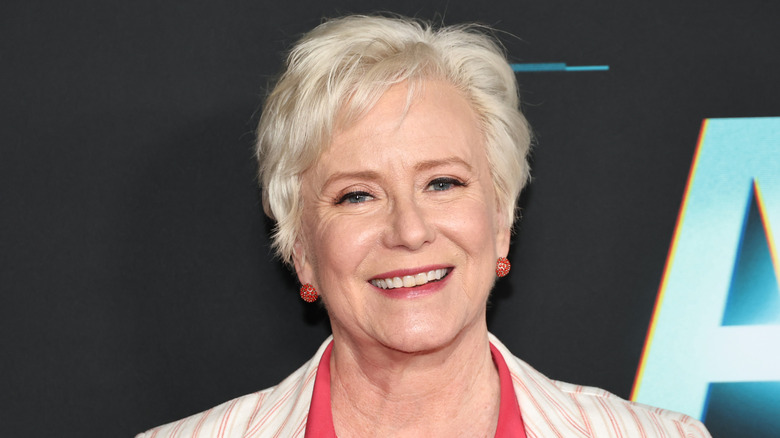 Eve Plumb wears a striped blazer while smiling for cameras on the red carpet