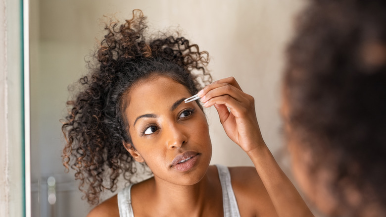 woman plucking her eyebrows