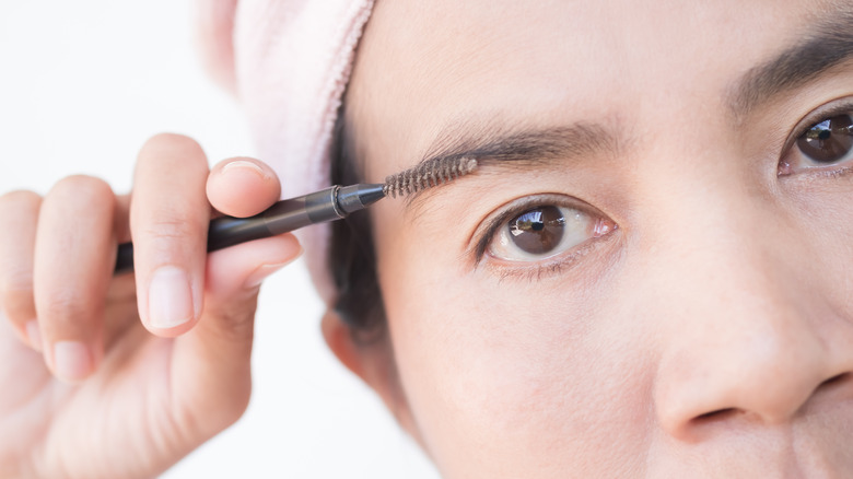 Woman brushing eyebrows with spoolie