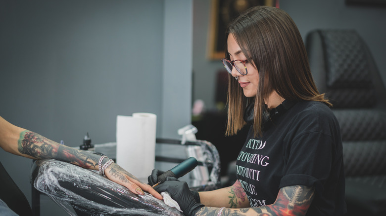 Tattoo artist working on hand tattoo