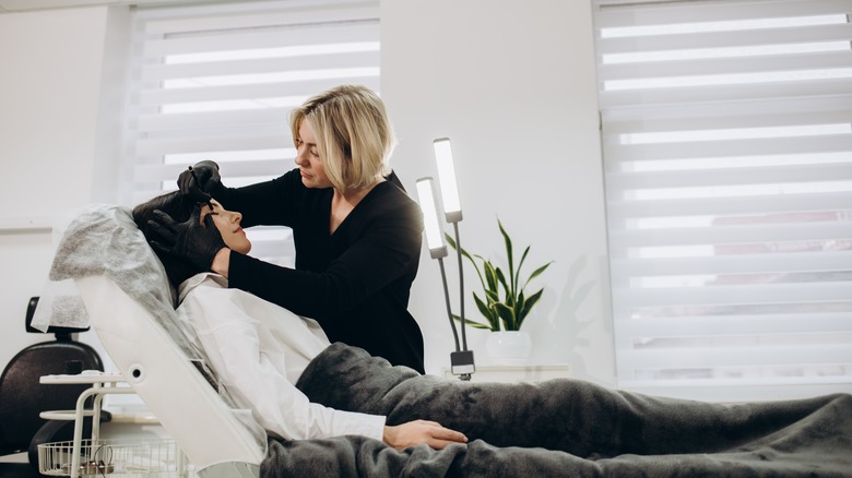 woman sculpting eyebrows in salon
