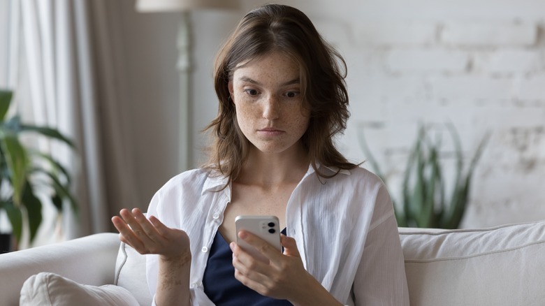 Woman looking at phone confused