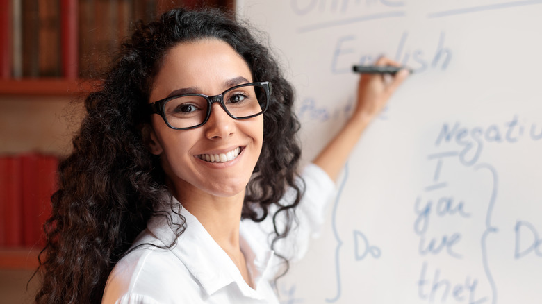 Person teaching grammar on whiteboard 
