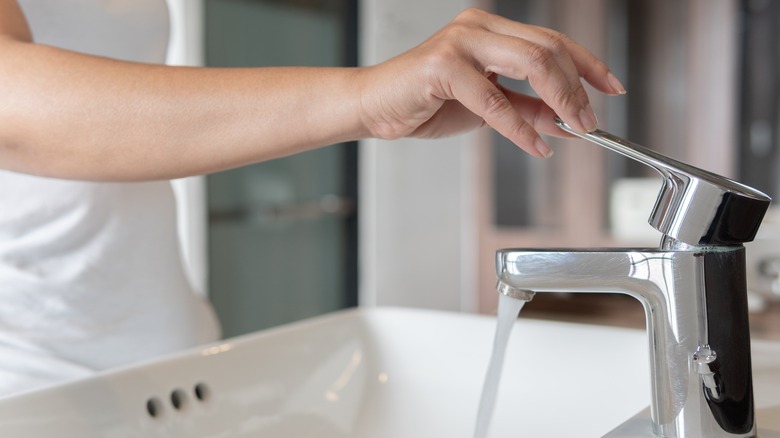 woman's hand using faucet with tap water