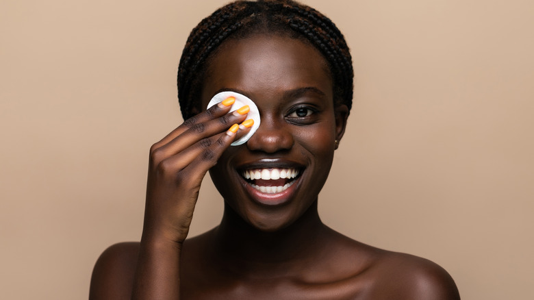 Woman cleaning her face with a cotton pad