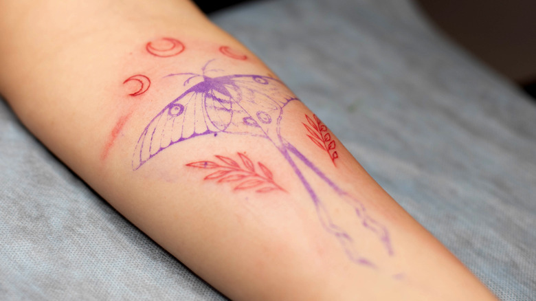 person getting tattoo on arm