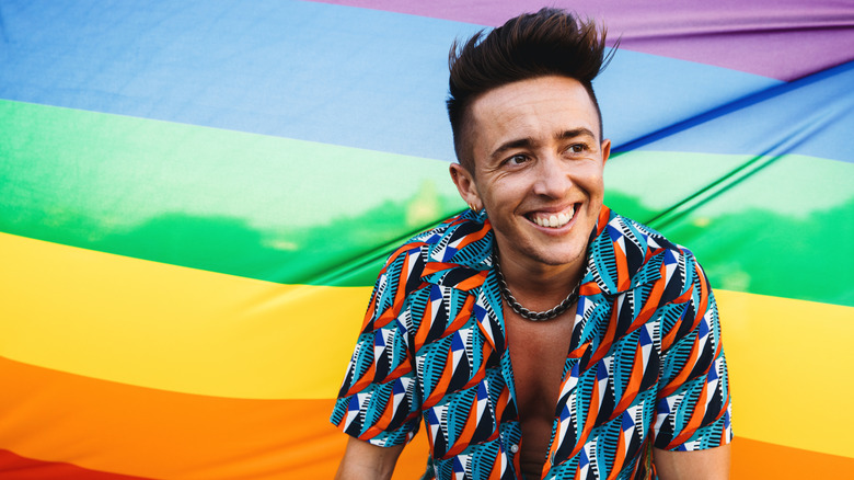Trans man in front of rainbow flag
