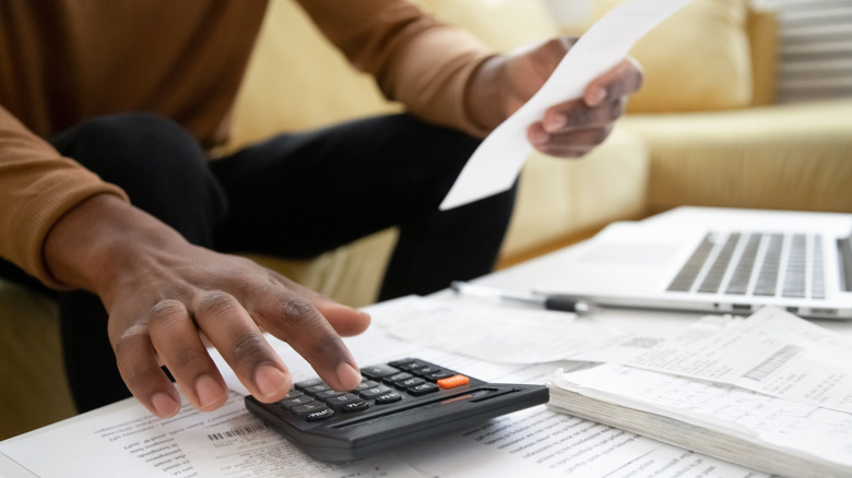 Person using calculator surrounded by paper