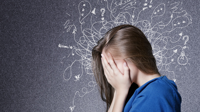 woman burying her face in her hands and looking overwhelmed