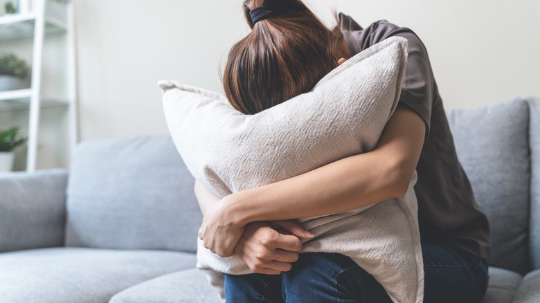 distressed woman burying her face in a pillow