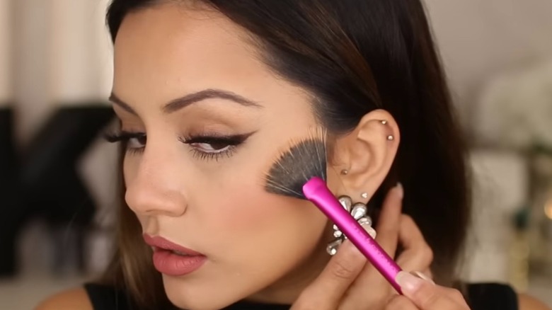 Woman applying makeup in the mirror 