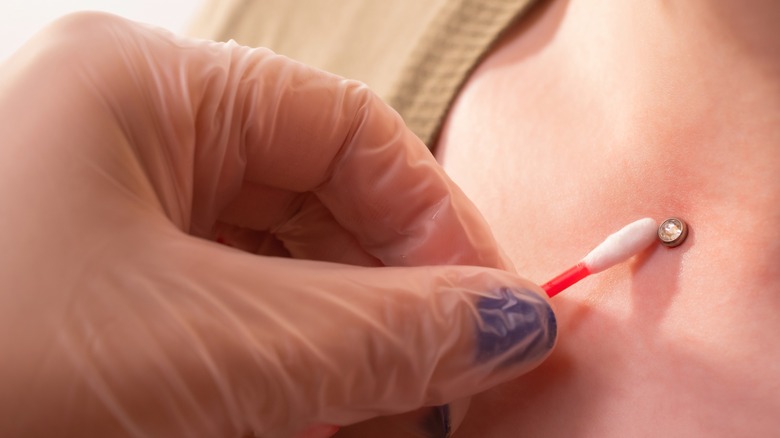 Person cleaning a dermal piercing 