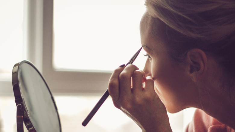 Woman applying eyebrow pencil