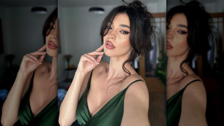 Woman poses with loose bun, bangs, and tendrils 