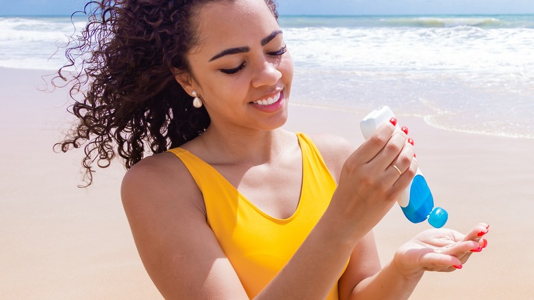 young woman applying sunscreen at beach
