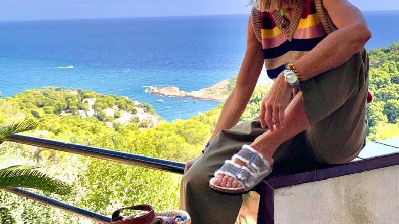 Women poses on balcony wearing fur lined sandals