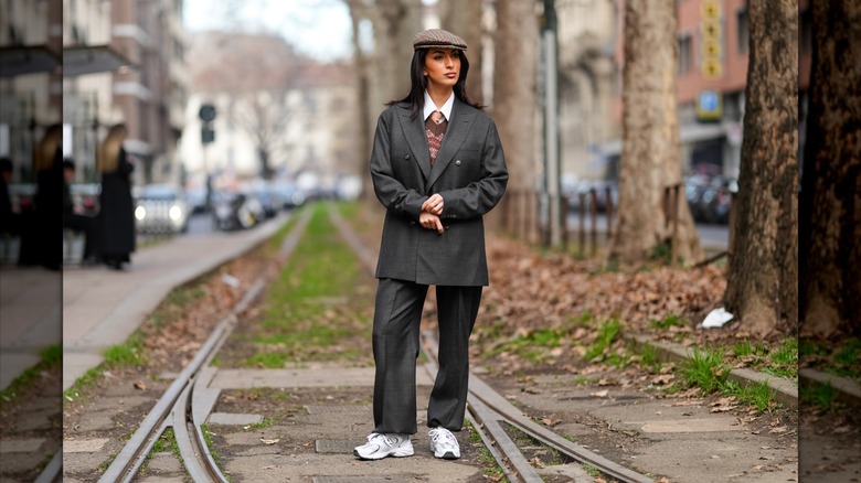 A person wears a suit, beret, and New Balance sneakers