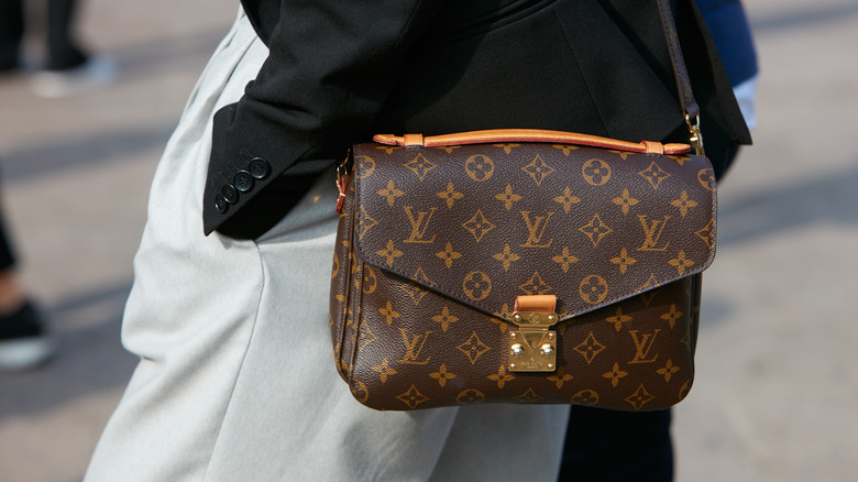 A person wearing a Louis Vuitton messenger bag