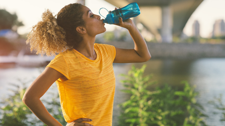 woman sipping water by river