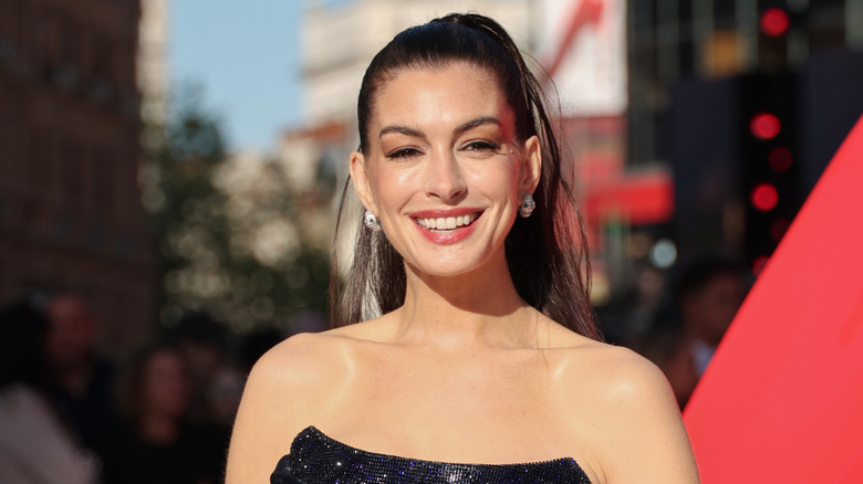 Anne Hathaway smiles in a sunny photo taken at an outdoor red carpet event