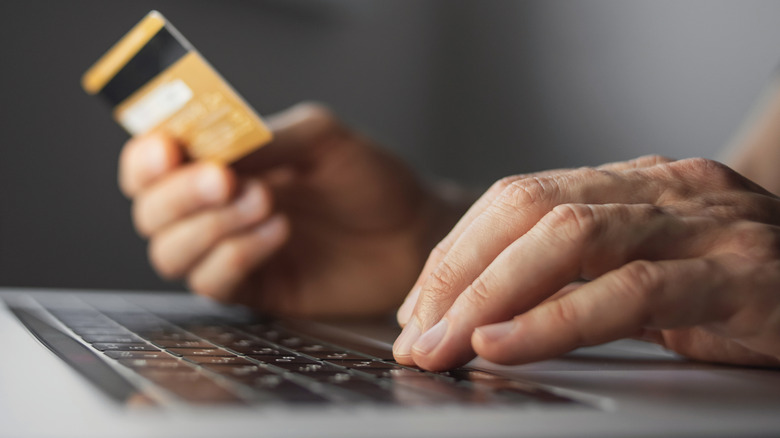 Model holding credit card while on laptop