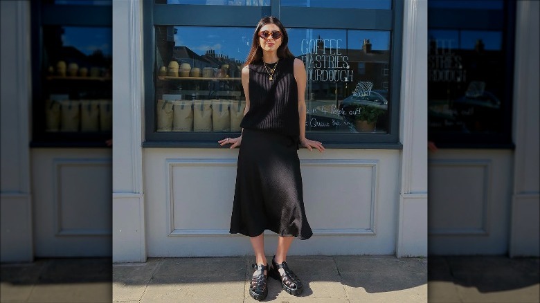 woman wearing black top, skirt, and fisherman sandals