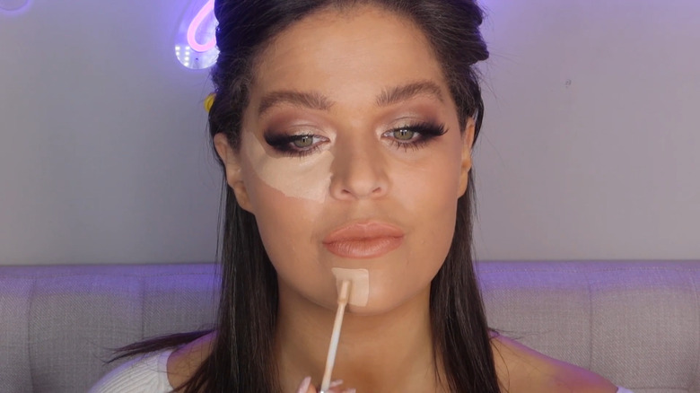 Woman applying concealer to chin