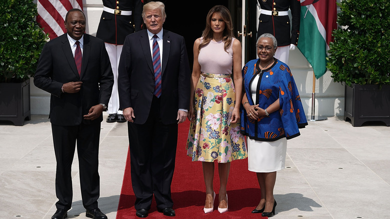 Melania Trump in a yellow floral skirt with Donald Trump and the president of Kenya and his wife