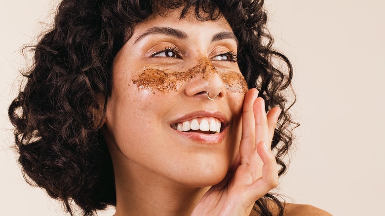 Smiling woman applying face scrub