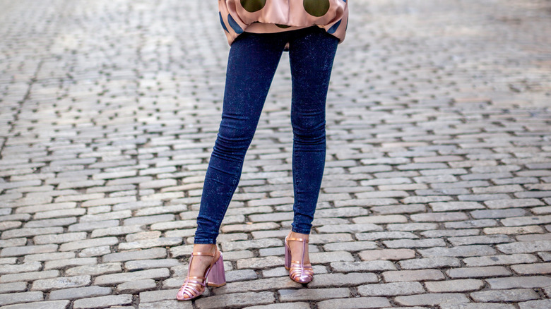 A women wearing skinny jeans and pink heels on the cobblestone streets of SoHo