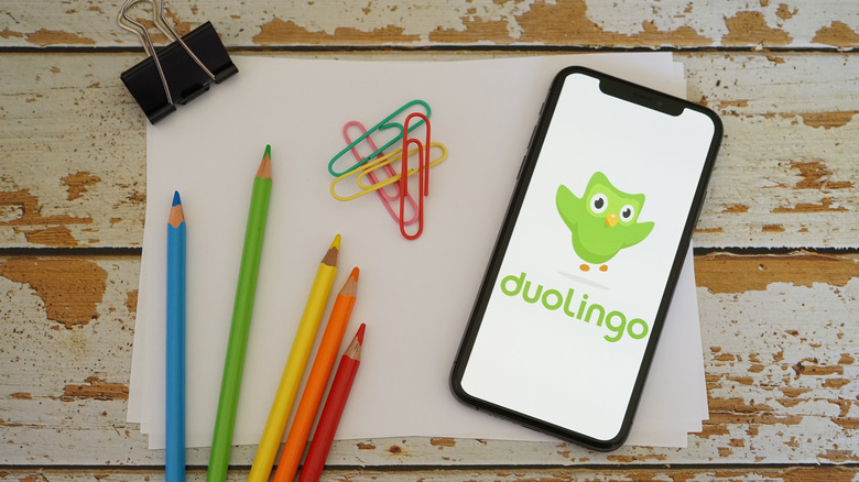 Clean sheets of paper featured with a phone with the Duolingo app