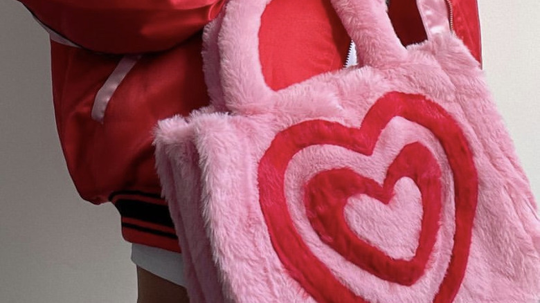 person holding pink fuzzy bag