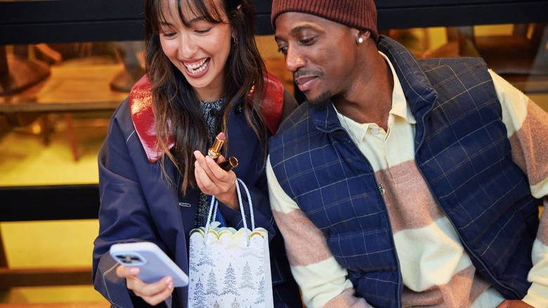 Two people smiling as they look at a phone screen