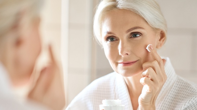 Mature woman applying skincare