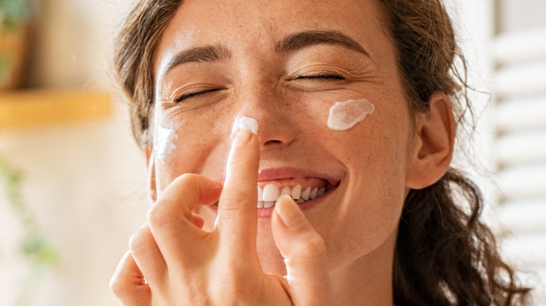 woman apply cream to her face
