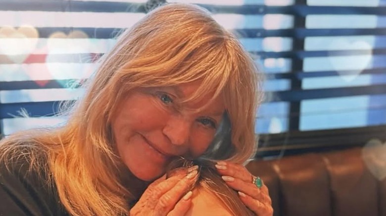 Goldie Hawn posing with her hands on her granddaughter's head in a candid photo.