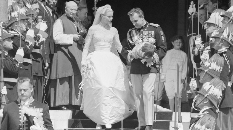 Black and white photo of Grace Kelly and Prince Rainier walking down stairs on their wedding day.