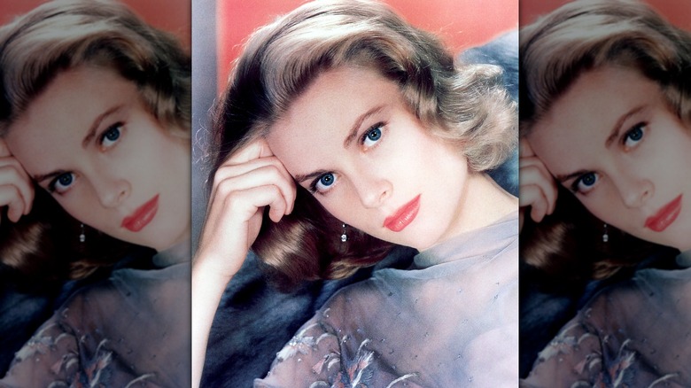 Grace Kelly posing with her head on her hand, wearing a gray top, simple makeup, and soft hair.