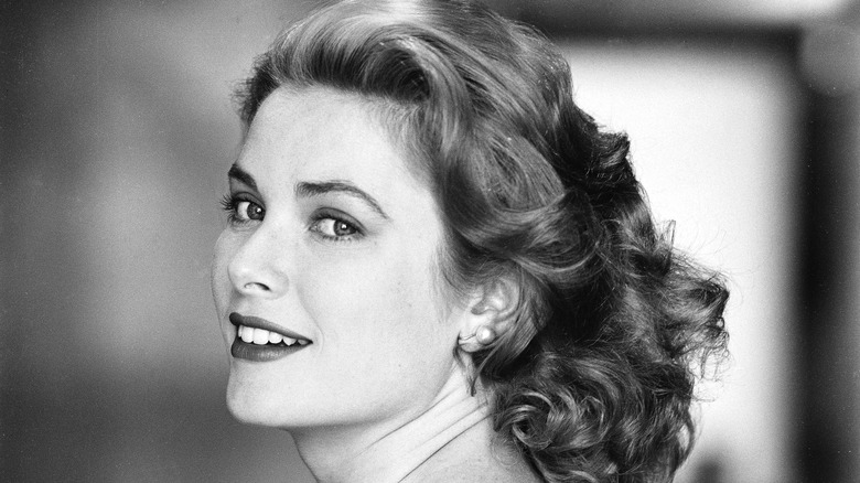 Black and white photo of Grace Kelly with her hair down, and face turned slightly towards the camera, smiling.