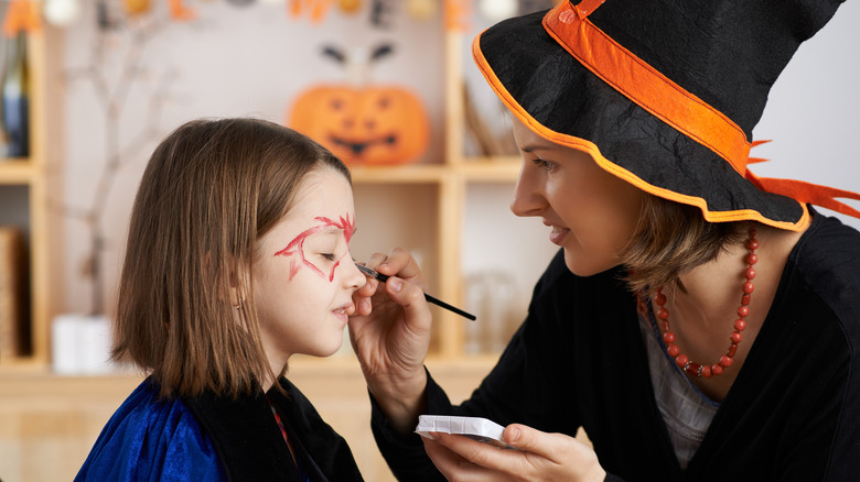 Mom doing Halloween makeup on child 
