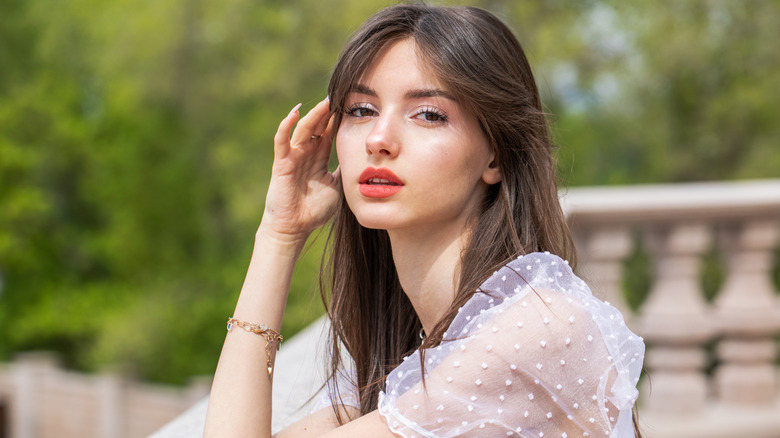A woman posing with side-swept curtain bangs in her brown hair