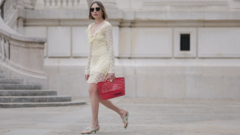 A woman color-blocking with a pale-yellow outfit and bright-red bag