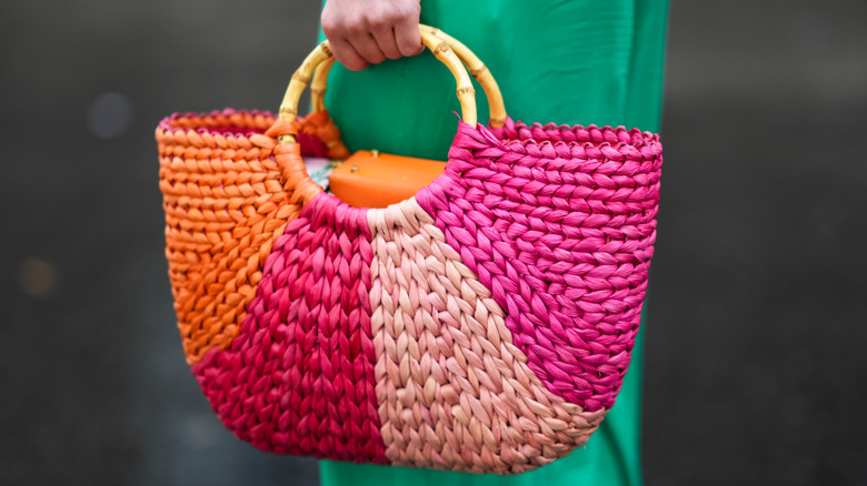 A person carrying a colorful raffia bag