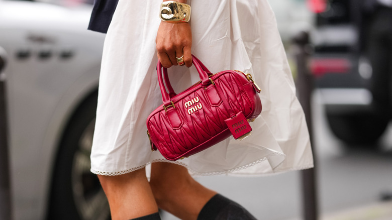 A woman carrying a small red leather handbag