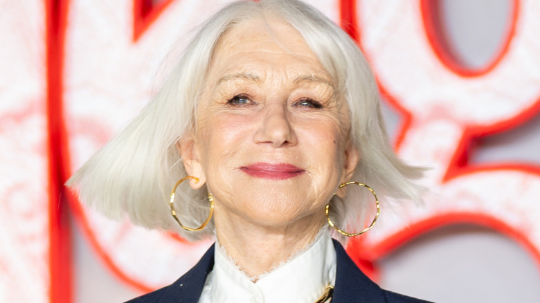 Helen Mirren posing on the red carpet wearing gold hoop earrings.