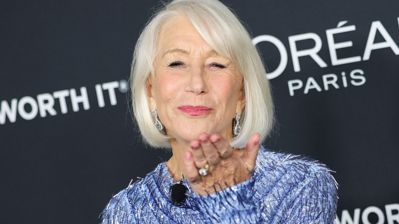 Helen Mirren wearing a blue gown and blowing a kiss on the red carpet.