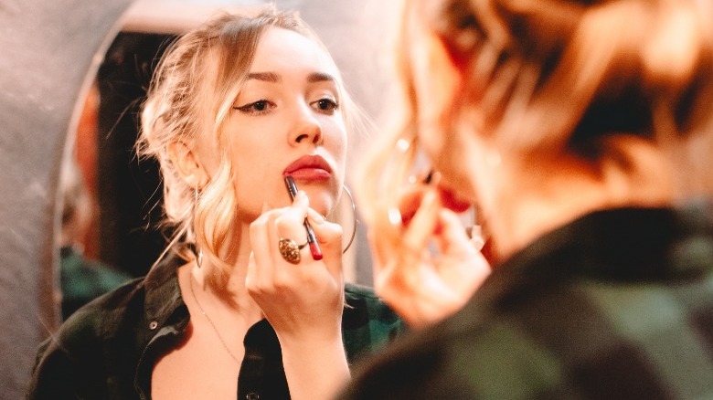 Blonde woman lining her lips