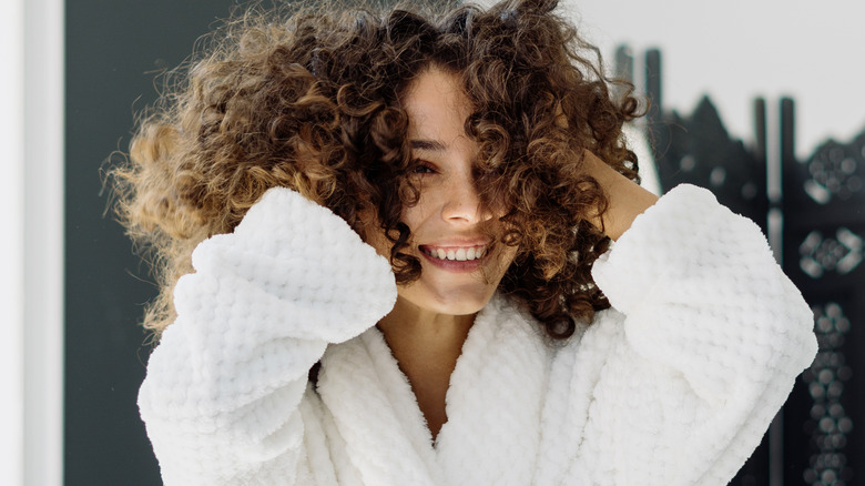 smiling woman with curly hair wearing bathrobe