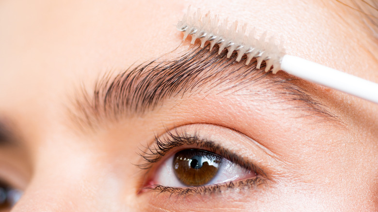 woman shaping eyebrows with spoolie